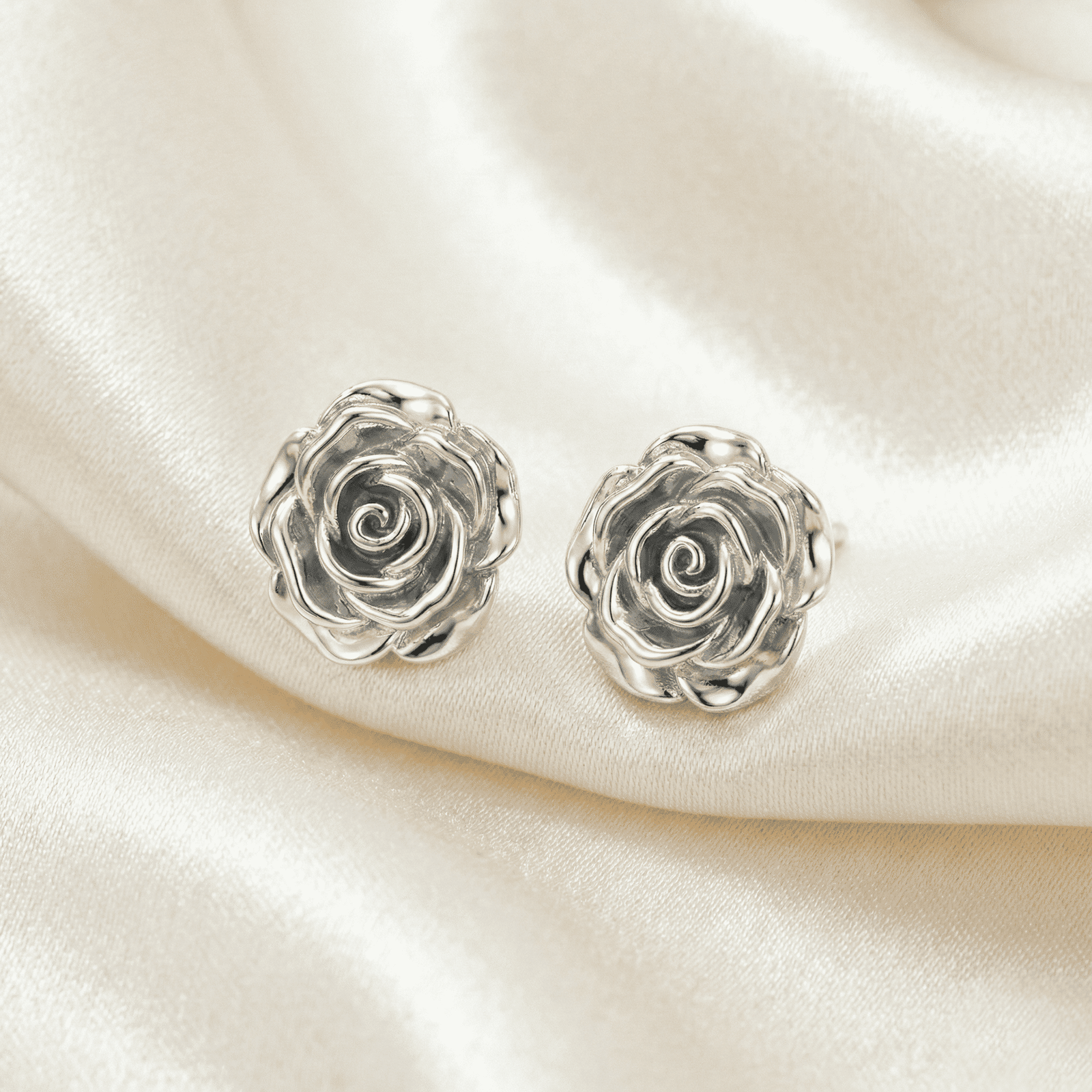 Silver floral stud earrings worn by woman front view