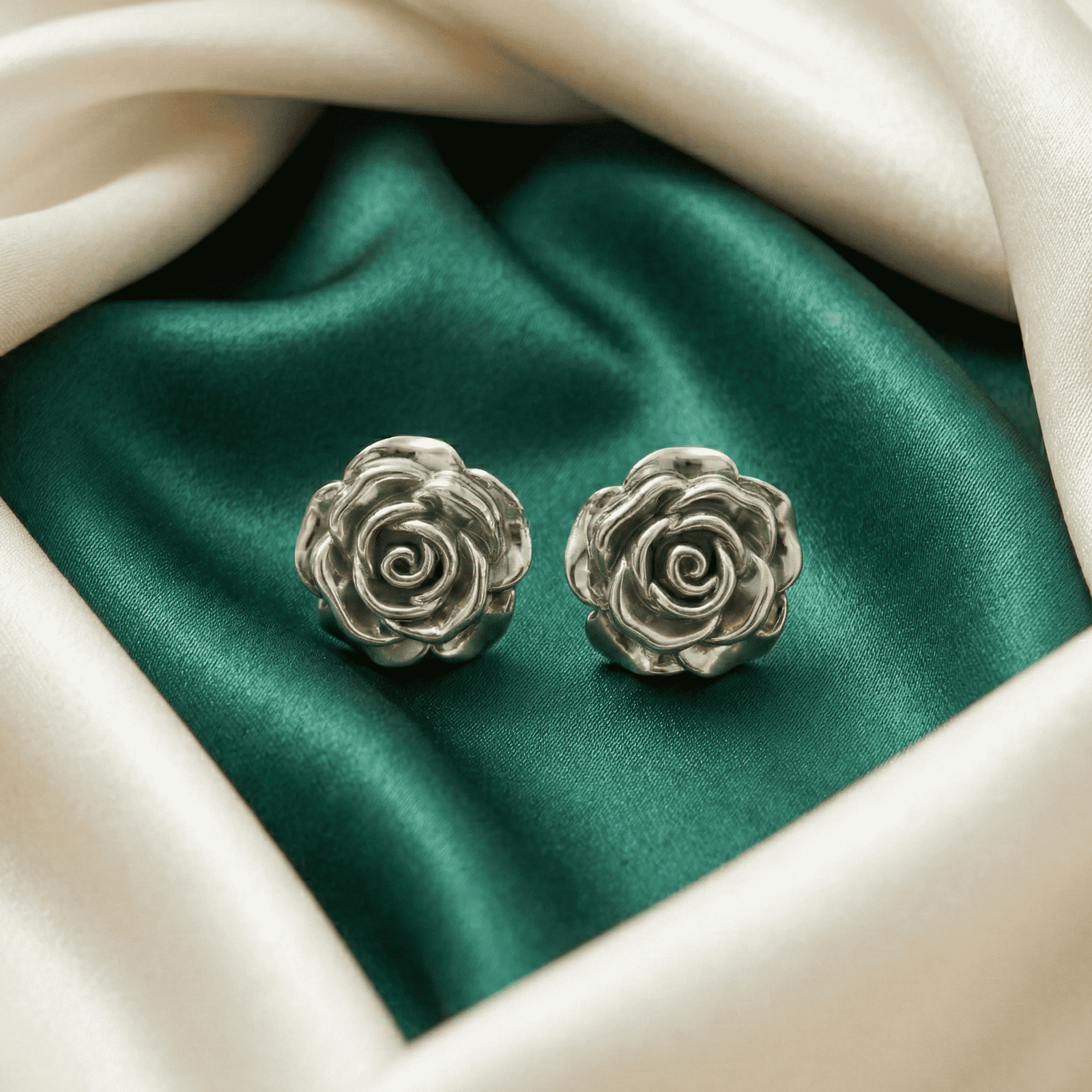 Silver rose stud earrings for women on satin background