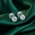 Silver tone crystal stud earrings for women on green satin fabric