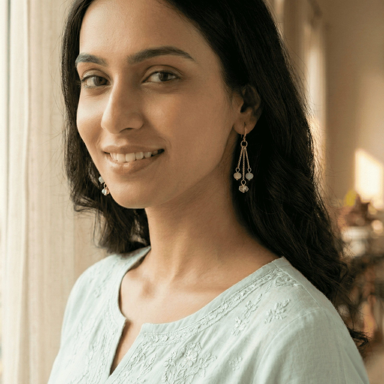 Woman styling pastel crystal drop hoop earrings with casual ethnic wear