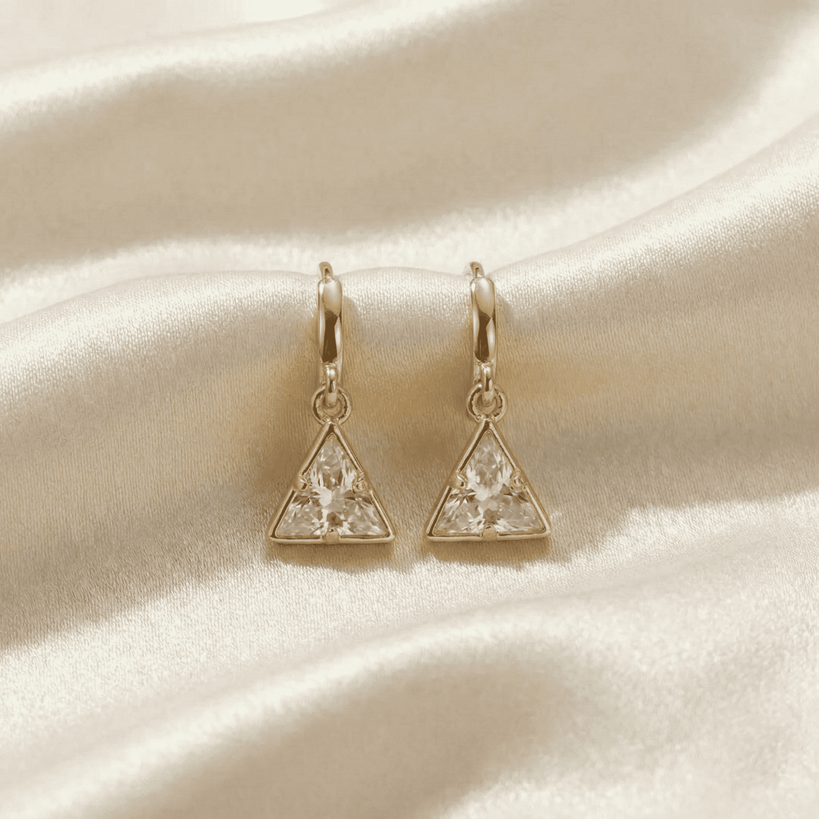 Stylish triangle crystal drop earrings on satin fabric