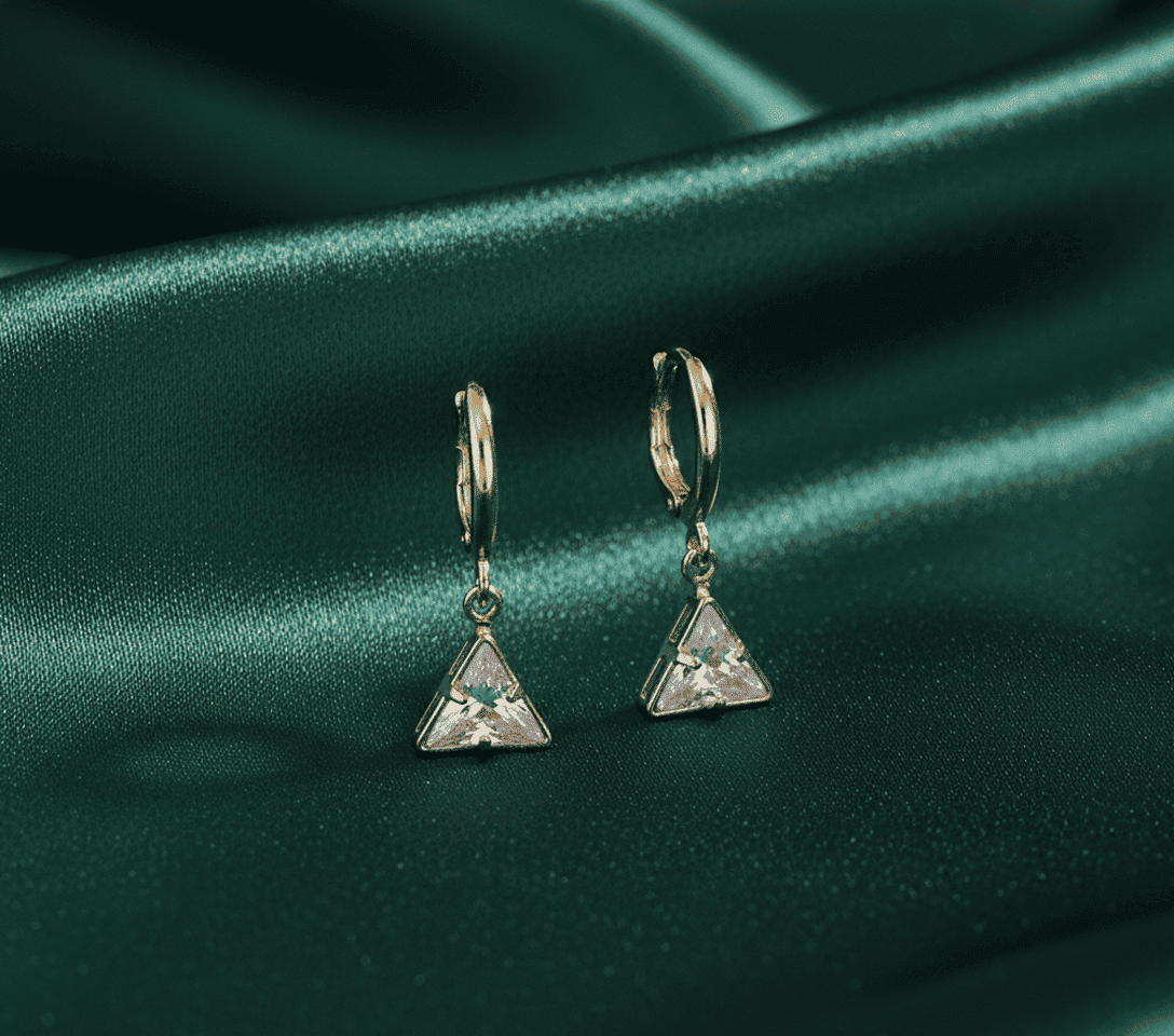 Triangle crystal earrings on green satin fabric