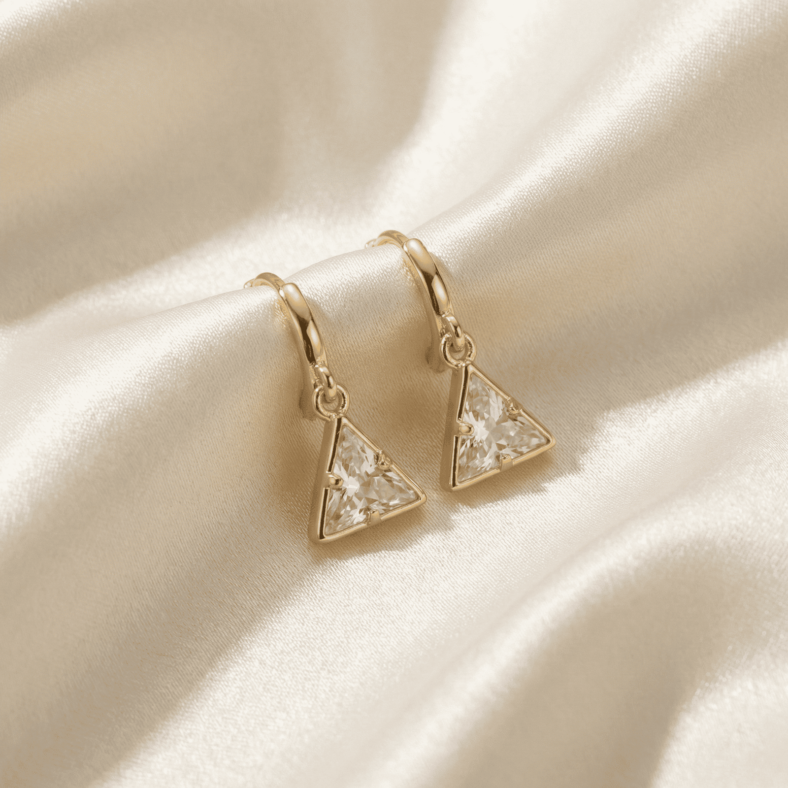 Modern gold tone crystal triangle hoop earrings on satin cloth
