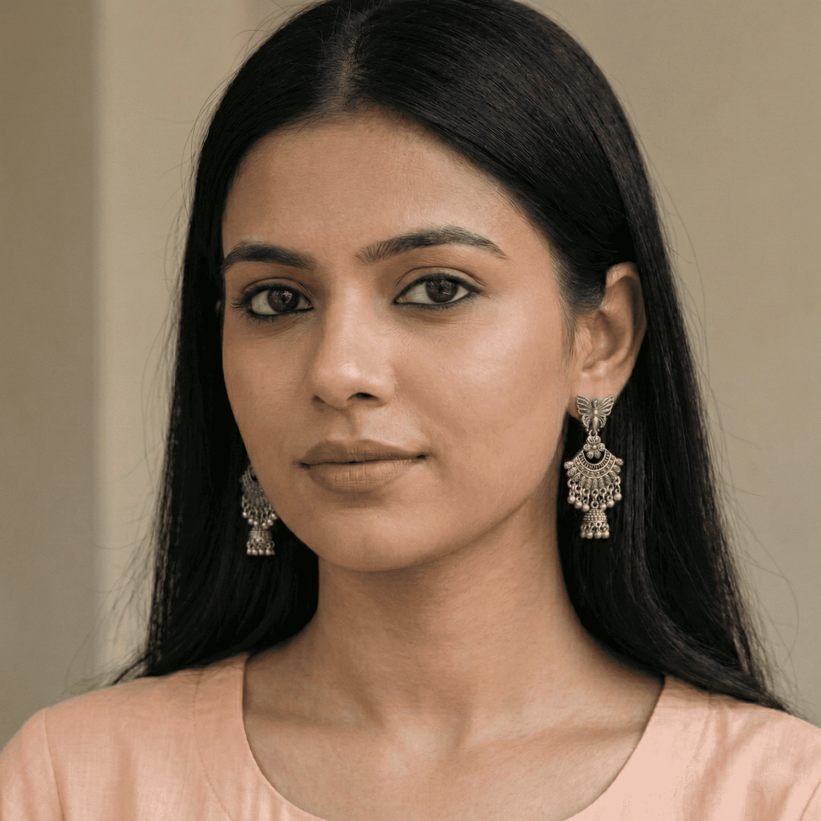 Woman wearing oxidised silver butterfly jhumka earrings with floral chandbali detailing and traditional bead drops