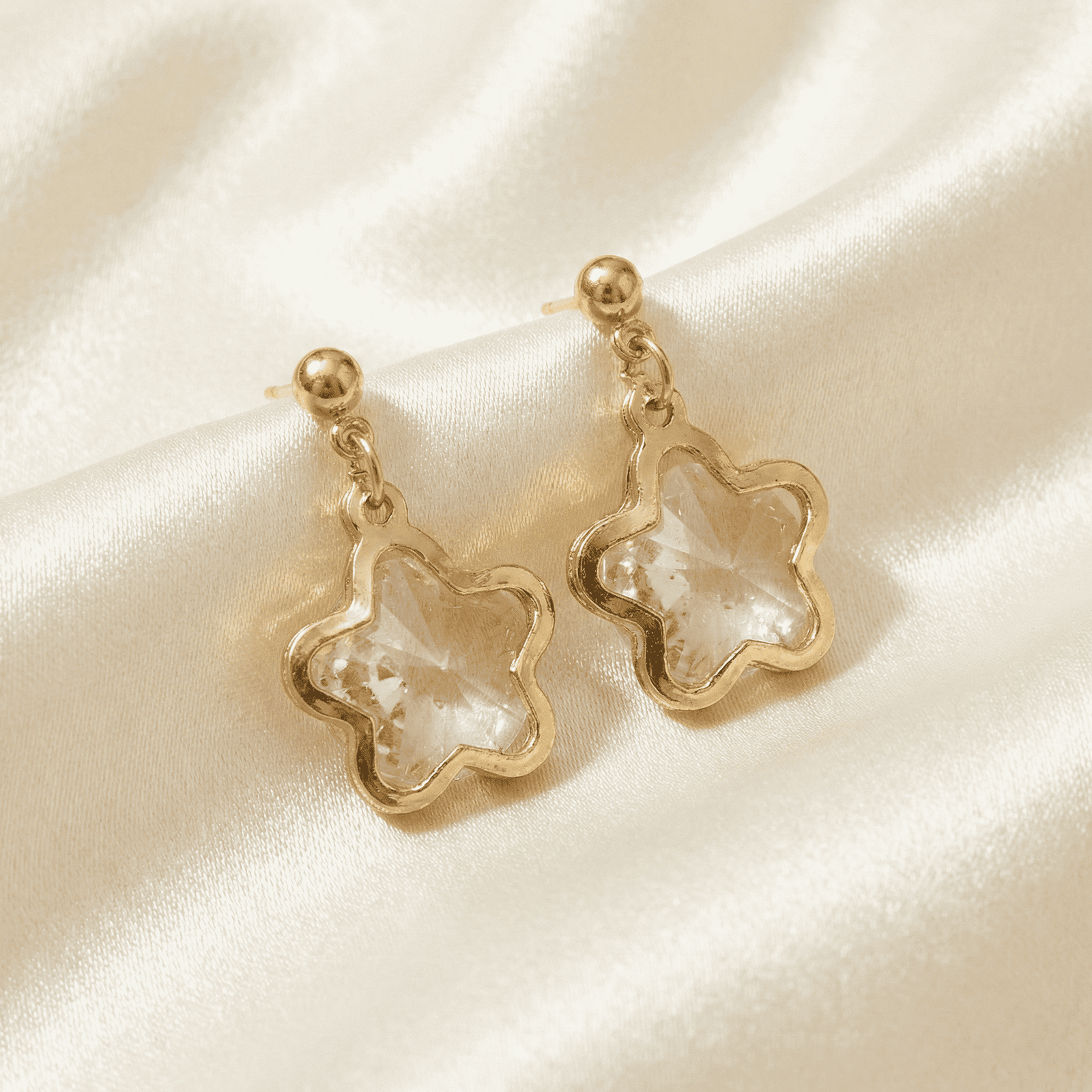 Star shape crystal dangle earrings for women displayed on ivory and green satin fabric