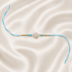Eshanarya Sky Blue Crystal Snowflake Designer Rakhi for Brother front view on off white satin cloth