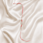 Eshanarya Red Crystal Snowflake Designer Rakhi for Brother on off-white satin background