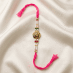 Designer Shree Rakhi with pearl beads and pink thread on off-white satin background for Raksha Bandhan
