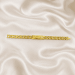 Eshanarya Gold Finish Engraved Bracelet Rakhi for Brother with rectangular engraved centre plate on an off-white satin background