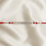 Horizontal Close-up of silver crystal Rakhi featuring multi-row crystal detailing and red bead accents