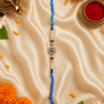 Blue Hamsa Evil Eye Designer Rakhi for Brother in a festive Raksha Bandhan setup with flowers, diya and kumkum.