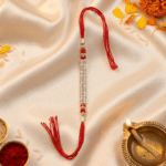 Silver crystal designer Rakhi for brother displayed on satin fabric with festive Raksha Bandhan setup