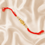 Angled view of Eshanarya Crystal Pearl Designer Rakhi featuring crystal decorative centrepiece, pearl-inspired beads and red Rakhi thread