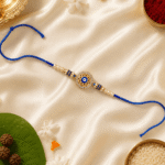 Beautiful Blue Evil Eye Rakhi with pearl detailing, crystal border and premium blue thread on festive satin background