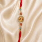 Close-up of premium Om Rakhi featuring crystal stones, pearl beads and traditional red thread