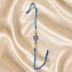 Eshanarya Blue Evil Eye Triangle Designer Rakhi featuring a protective Nazar motif with pearl beads and crystal embellishments.
