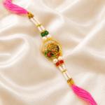 Angled view of designer Shree Rakhi with pearls, enamel work and pink thread