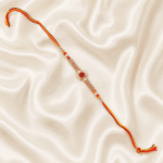 Top view of Eshanarya premium red crystal rakhi with traditional sacred thread