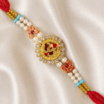 Angled close-up of Om designer rakhi with gold-tone finish and sparkling crystal embellishments