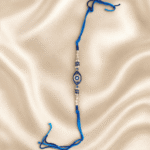 Blue Nazar Designer Rakhi for Brother featuring a crystal evil eye centrepiece, pearl accents and braided blue thread for Raksha Bandhan.