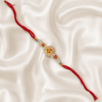 Diagonal flat lay of premium Om Rakhi on elegant satin cloth for Raksha Bandhan gifting