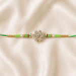 Close-up horizontal image of green crystal designer Rakhi with decorative pearl and golden beads