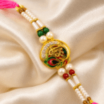 Premium Shree designer rakhi with pearl detailing displayed on green satin fabric