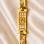 Vertical close-up of Eshanarya Om Bracelet Rakhi with crystal-studded centreplate and polished gold finish bracelet links