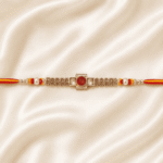 Horizontal view of Eshanarya Regal Ruby Bracelet Rakhi on luxury satin fabric
