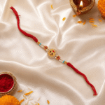 Festive Om designer rakhi with diya, kumkum and marigold flowers on satin background