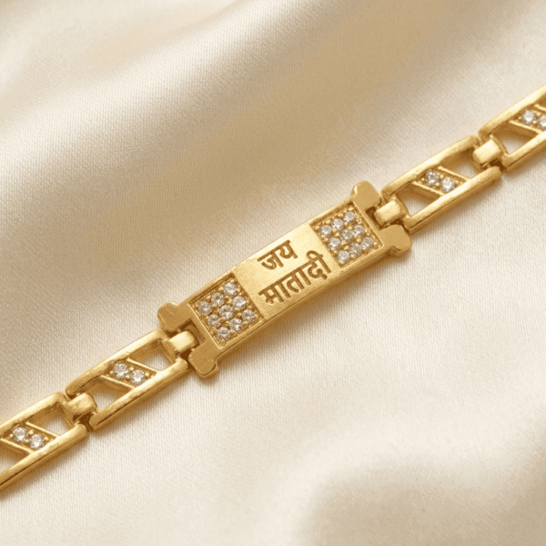 Macro image of Jai Mata Di Bracelet Rakhi featuring engraved devotional text with crystal detailing and gold-tone finish.