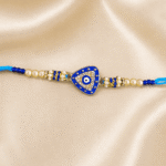Minimalist Blue Evil Eye Rakhi with a triangle-shaped Nazar motif, crystal embellishments and pearl bead design.