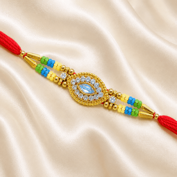 Angled close-up of gold crystal designer Rakhi featuring eye-shaped centerpiece