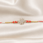 Close-up of crystal snowflake designer Rakhi with red beads and gold-tone detailing