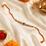 Luxury Raksha Bandhan flat lay featuring Eshanarya Regal Ruby Bracelet designer rakhi with festive décor