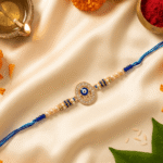 Blue Hamsa Evil Eye Designer Rakhi displayed with diya, kumkum and festive décor for Raksha Bandhan celebrations.